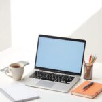 Apple MacBook Air M2 on a modern student desk with notebooks and coffee, bright natural light, minimalist study setup